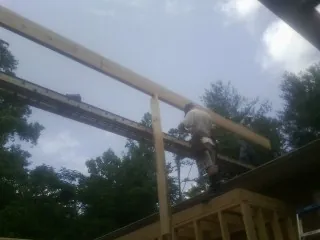 Carpenter setting a ridge beam over a new addition frame — Ice Dam Removal by Roofing Brothers in Nye
