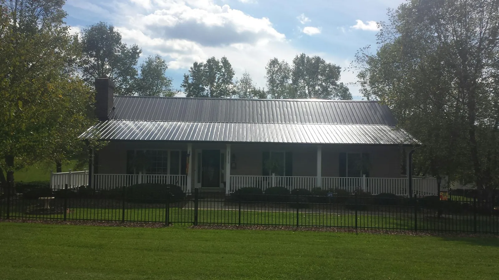 Gray metal roof on a brick ranch with a full width front porch — Gutter Guard Installation work by our crew in Nye