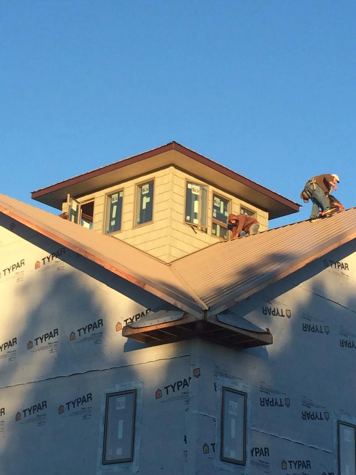 Roofers working around a rooftop cupola on a new metal roof at sunset — Roof Waterproofing in Nye by Roofing Brothers